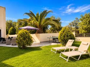 a lawn with two chairs and an umbrella at Villa Rose Ground Floor - Private Swimming Pool Garden in Koskinou