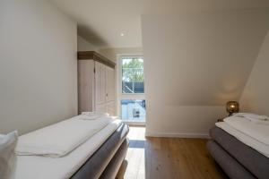 two beds in a room with a window at Strandhaus Zingst Apartment 16 in Zingst