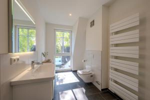 a bathroom with a sink and a toilet and a window at Strandhaus Zingst Apartment 16 in Zingst +22 photos