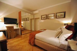 Habitación de hotel con cama, escritorio y TV. en Angel Spagna Suite, en Roma