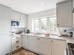 a white kitchen with white cabinets and a sink at 1 Bed in Sheffield oc-48259 in Thurlstone