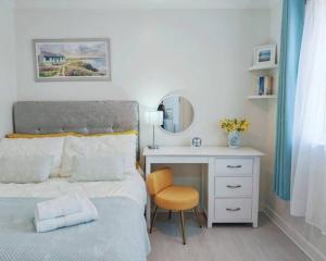 a bedroom with a bed and a desk with a mirror at Fully accessible bungalow by the Beach in Port Talbot