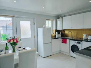 a kitchen with a white refrigerator and a table with chairs at Fully accessible bungalow by the Beach in Port Talbot