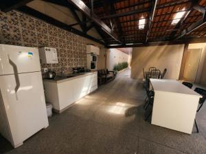 a kitchen with white cabinets and a white refrigerator at Flamboyant Stay Rooms in Goiânia
