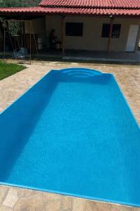 a blue swimming pool in front of a house at Rancho Patrocínio in Patrocínio
