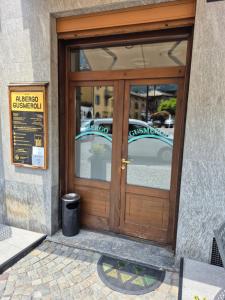 a wooden door of a building with a trash can at Albergo Gusmeroli in Tirano