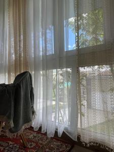 a room with white curtains and a chair in front of a window at TAGANI Guest Rooms in Martuni