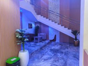 a lobby with a staircase and a table and a chair at Smich Suites in Abuja