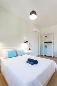 a white bedroom with a large white bed with blue pillows at Coastline Studio Apartment Ligia Bay in Lygia