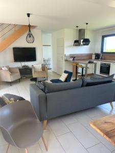 a living room with a gray couch and a kitchen at Le jardin de la mer in Wierre-Effroy