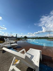 a pool of water with white lounge chairs next to it at Apartahotel Paraíso Cafetero Guaduales del café 401B in Montenegro
