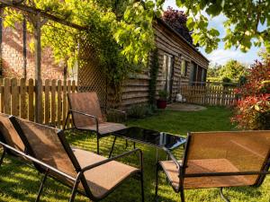 two chairs and a glass table in a yard at The Barn at White Rose Cottage in Towcester