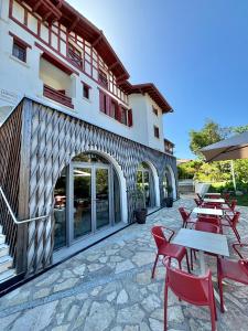 a patio with tables and chairs in front of a building at Hôtel & Résidence Vacances Bleues Orhoïtza in Hendaye