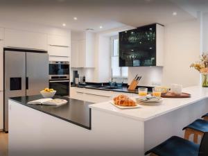 a kitchen with white cabinets and a black counter top at Villa Le Cep - OVO Network in Menthon-Saint-Bernard