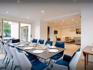 a dining room with a long table and blue chairs at Villa Le Cep - OVO Network in Menthon-Saint-Bernard