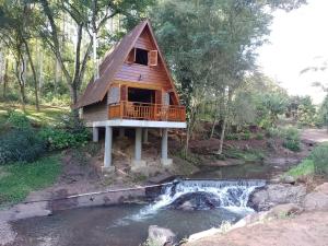 a cabin in the woods with a creek and a house at Cabanasdoaconchego in São Salvador