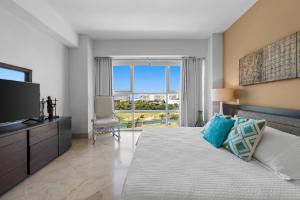 a bedroom with a large bed and a television at Luxury Beach Condo with Resort Access Vidanta in Nuevo Vallarta