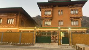 a large orange building with green doors and a fence at Tshang Tshang Villa in Paro