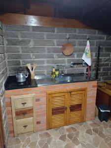 a kitchen with a sink and a brick wall at Cabanasdoaconchego in São Salvador