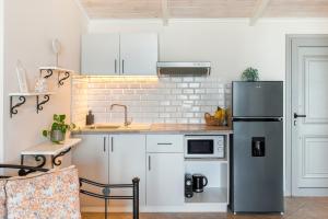 a kitchen with white cabinets and a refrigerator at Garden Studios in Alykes