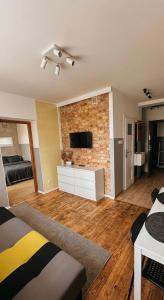 a living room with a television and a brick wall at Apartamenty W Domu in Białystok