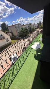 a balcony with a white table and chairs and a fence at Apartamenty W Domu in Białystok