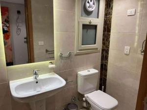 a bathroom with a sink and a toilet and a mirror at SUNSKY Apartment Hotel in New cairo +8 photos