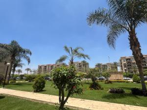 a park with palm trees and buildings in the background at SUNSKY Apartment Hotel in New cairo