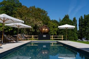 a pool with a statue and two umbrellas at Château du Portereau in Vertou +49 photos