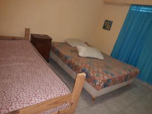 two beds in a room with blue curtains at Ruca in Bragado