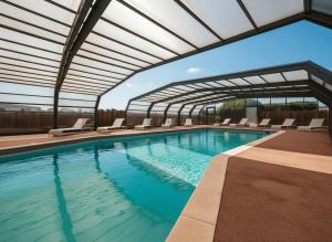 a large swimming pool with chairs and an umbrella at Retour de Plage in Saint-Pair-sur-Mer