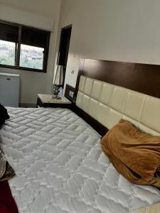 a bedroom with a large white bed with a headboard at Ahmmad in Şirfah