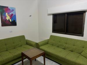 a living room with two green couches and a table at Ahmmad in Şirfah