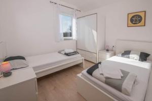 a white room with two beds and a window at Holiday house Casa Vida in Rakalj