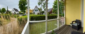 a porch with a white fence and a yellow house at Villa Iduna mit modern desingten Apartments in Graal-Müritz