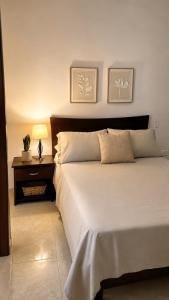 a bedroom with a large white bed and a night stand at Espectacular! Apartamento en cali cerca al coliseo del pueblo in Cali