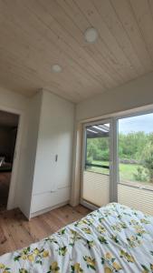 a bedroom with a bed and a large window at Wiosłem w Hamaku Domek nad Wkrą in Rybitwy