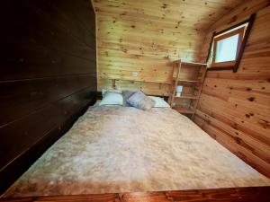 a large bed in a wooden cabin with a window at RED Tiny Houses in Voronet