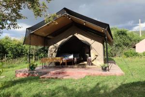 a black tent with a bench in a field at SaitotiMara Safaris in Sekenani