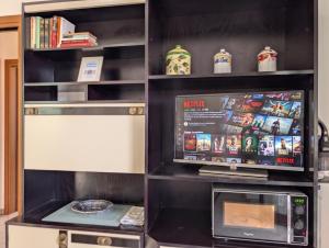 a book shelf with a tv and a microwave at -1 min dal mare- AC balcone e garage in Pedaso