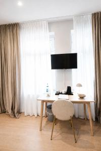 a desk with a chair in a room with curtains at Hotel Schloss Teutschenthal in Teutschenthal