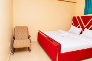 a bedroom with a red bed and a chair at Almarg homes in Nakuru