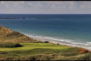a golf course with the ocean in the background at Portstewart promenade apartment with sea views in Portstewart