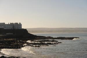 a view of the ocean with a castle in the background at Portstewart promenade apartment with sea views in Portstewart +26 photos
