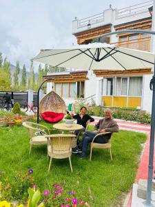 two people sitting at a table under an umbrella at Rongmo villa in Leh