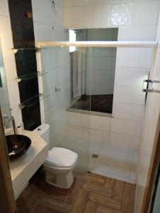 a bathroom with a toilet and a glass shower at Pousada Marlin in Dois Vizinhos