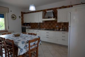 a kitchen with white cabinets and a table with chairs at Natura e Relax Casa Emma in Buonvicino