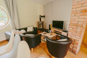 a living room with black leather chairs and a tv at Beachside Guest House Piejuras nams in Ķesterciems