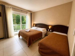 a hotel room with two beds and a window at Pousada Nosso Lar in Gramado +39 photos