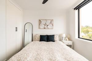 a white bedroom with a bed and a window at Richmond apartment close to MCG in Melbourne